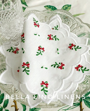 Mistletoe sprigs scattered on scalloped linen cocktail napkins. Recreated from our vintage embroidered linen collection.